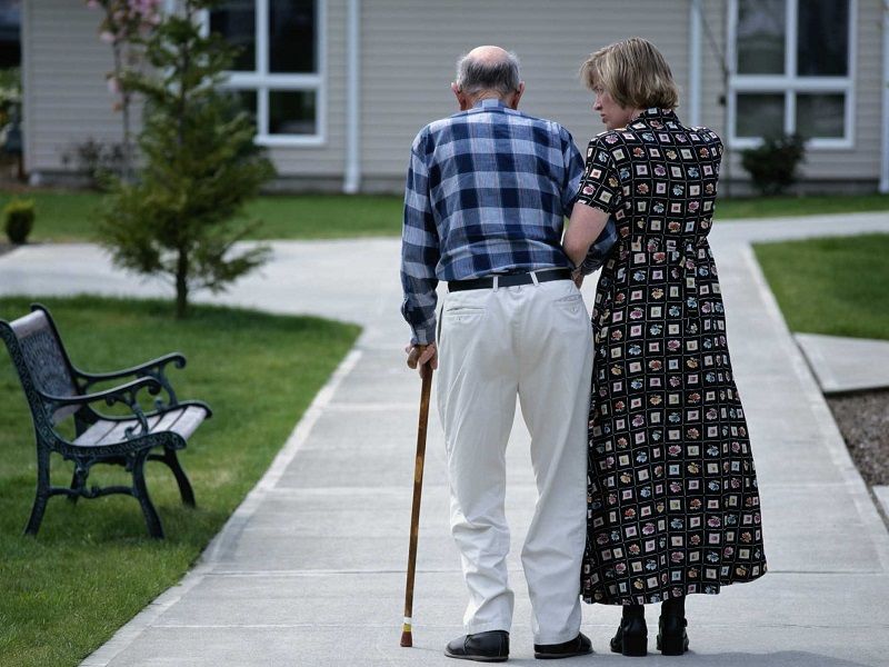 Un homme age soutenu par un aidant familiale