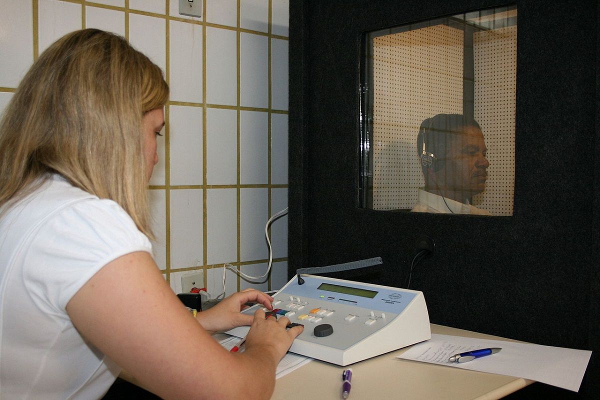 Un professionnel de la santé auditive effectuant un test auditif audiométrique dans une cabine de test insonorisée c9ac3