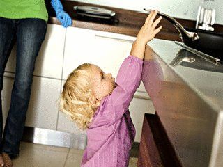 Un enfant près d'une cuisinière tentant de prendre le manche d'une casserole un accident qui coûte souvent très chère a nos enfants